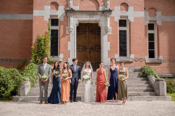 Bride groom bridesmaids and groomsmen walk in the sunshine together